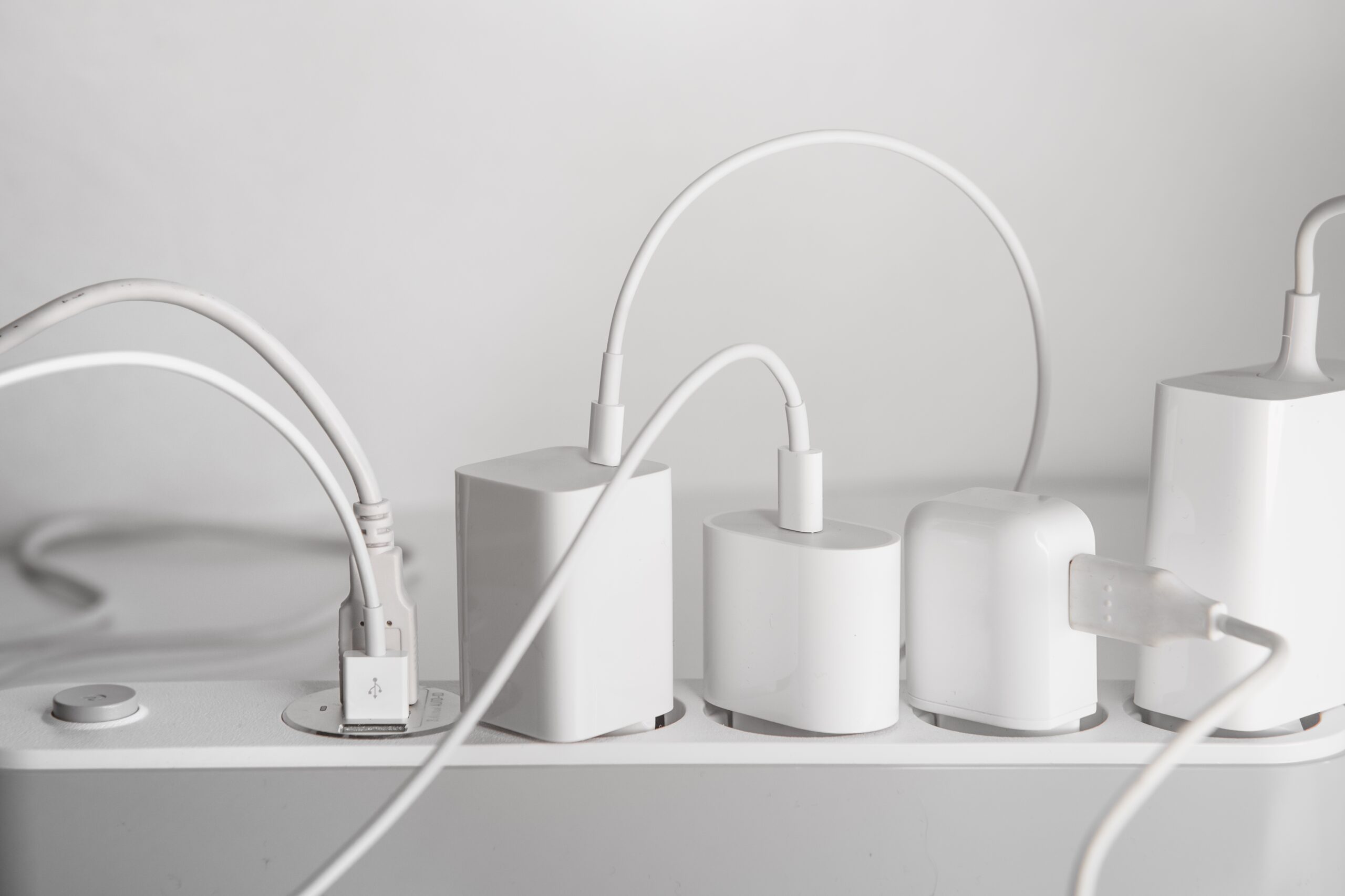 Overloaded power strip with multiple phone chargers plugged in, showing why built-in USB outlets are a safer and more convenient solution for Twin Cities families.